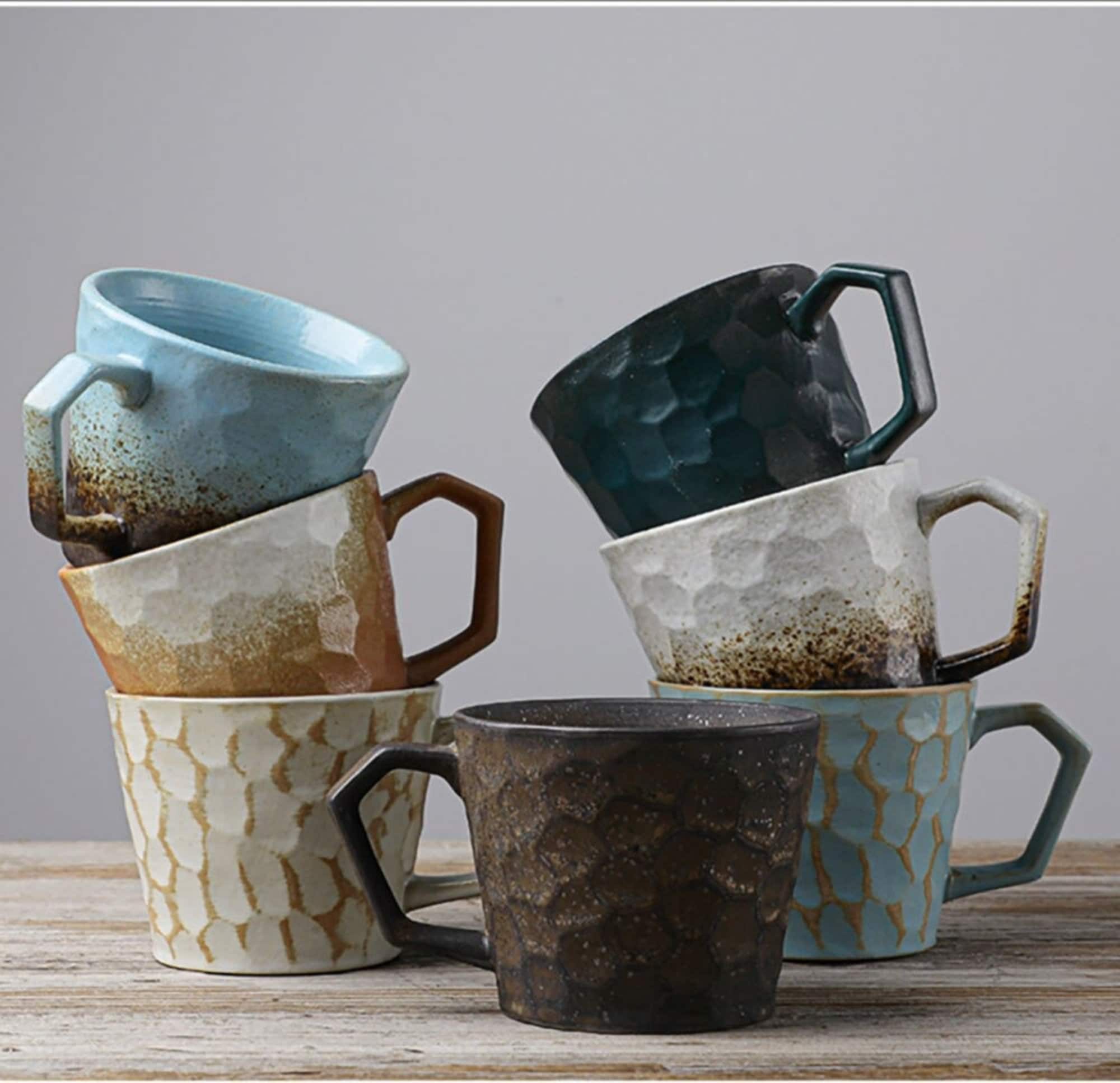 Stack of vintage Japanese style stoneware coffee cups in earthy tones and a light blue.